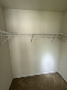 Empty closet with white wire shelving and beige carpet.