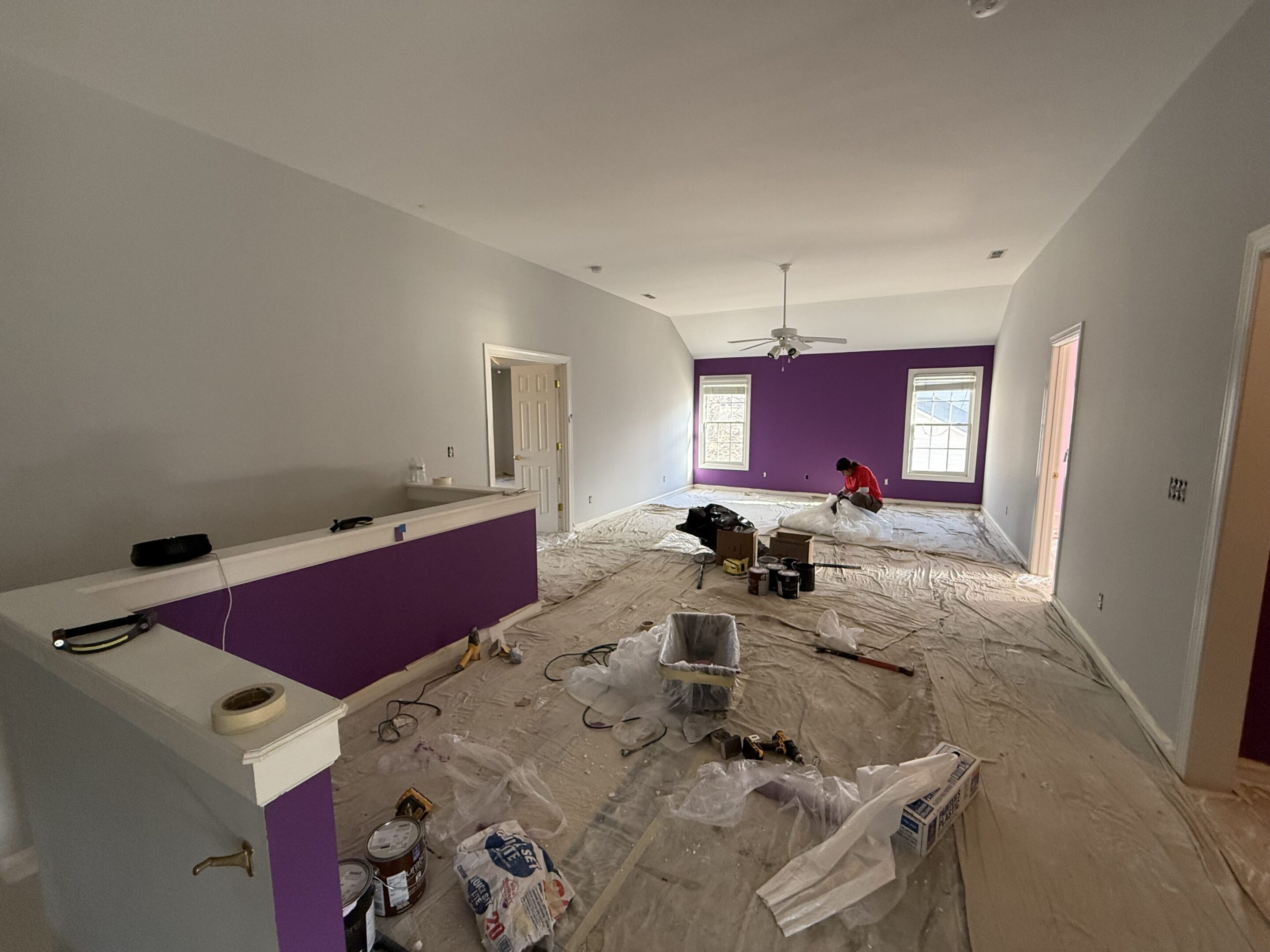 Room under renovation with purple accent wall and scattered debris.