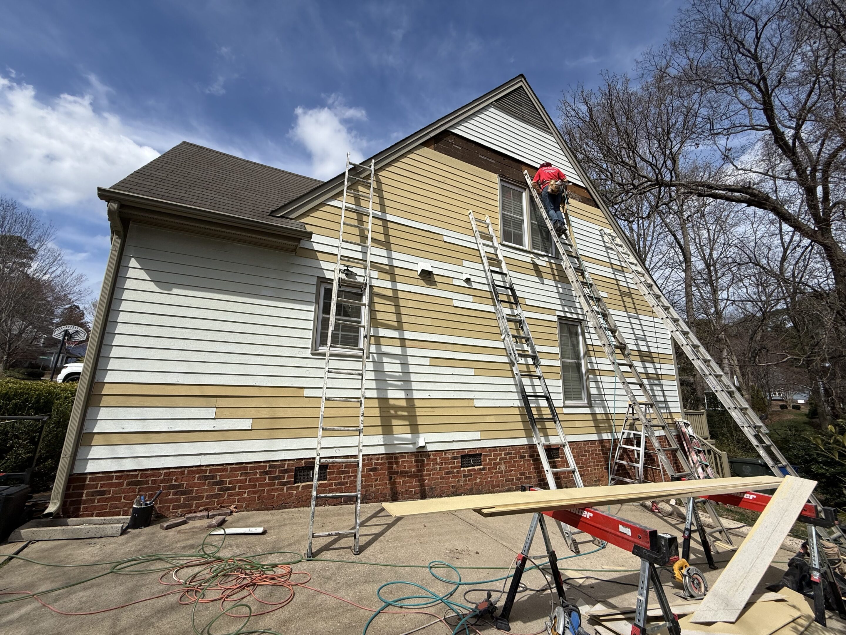 Workers painting a house exterior with scaffolding setup.