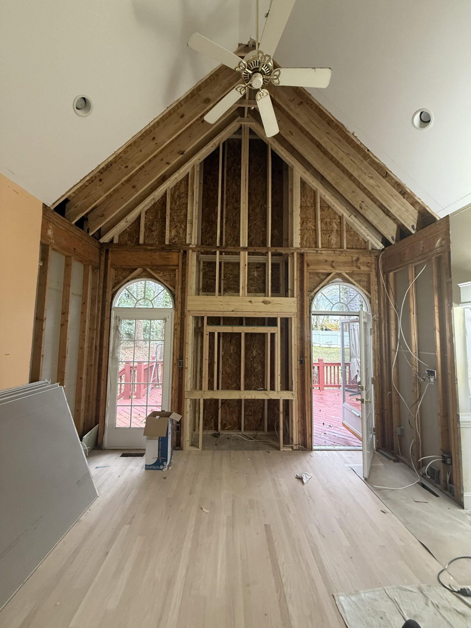 Interior of a house under construction with exposed beams and arched windows.