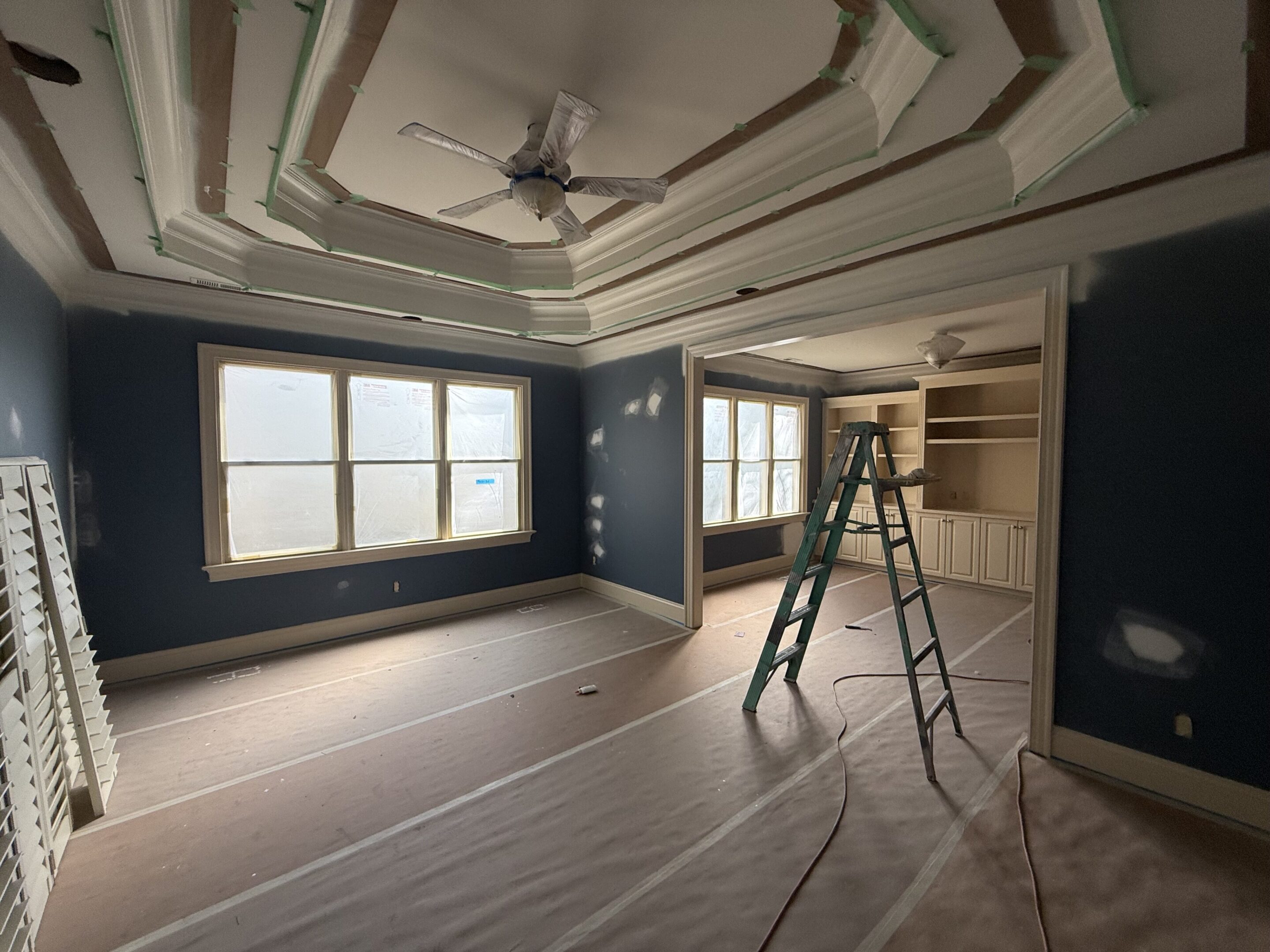 Room under renovation with a ladder and covered floor.