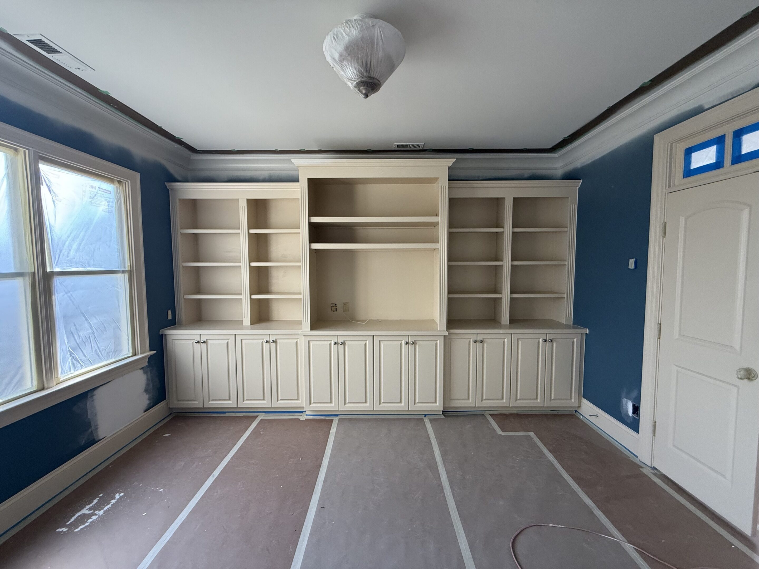 Built-in white cabinetry with shelves and cupboards in a blue room.
