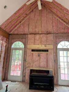 Insulated wall and ceiling with windows and a fireplace in a room under construction.