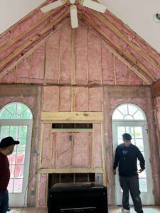 Two workers installing insulation in a house under construction.