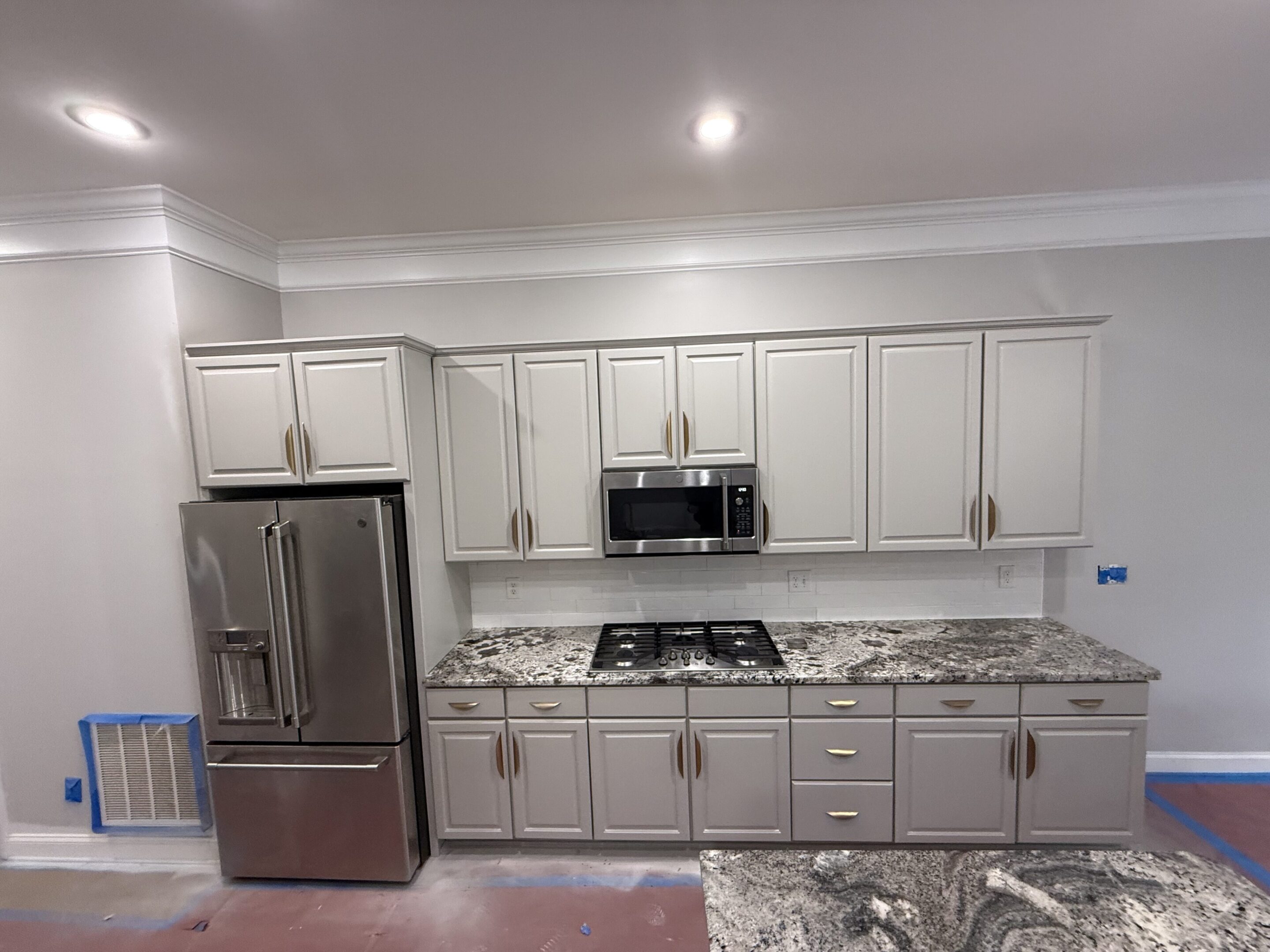 Modern kitchen with white cabinets and stainless steel appliances.