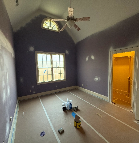 A room under renovation with tools and paint supplies on the floor.
