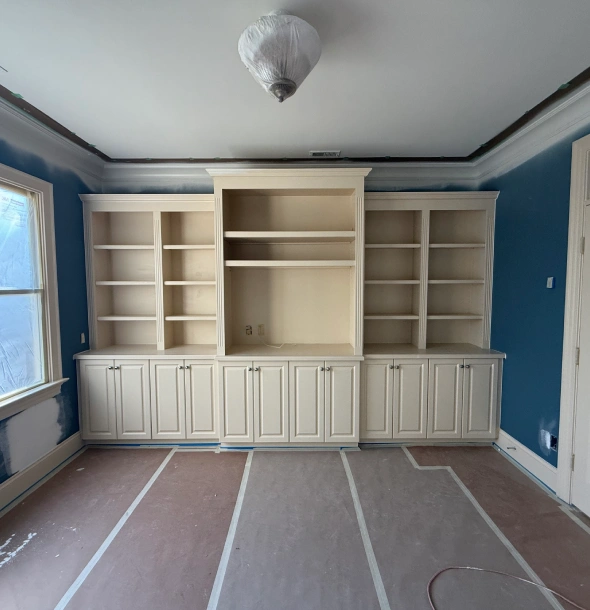 Built-in white shelving unit against blue walls in a room under renovation.
