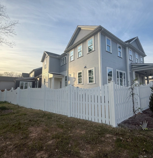 A two-story house with a white picket fence and a clear sky.