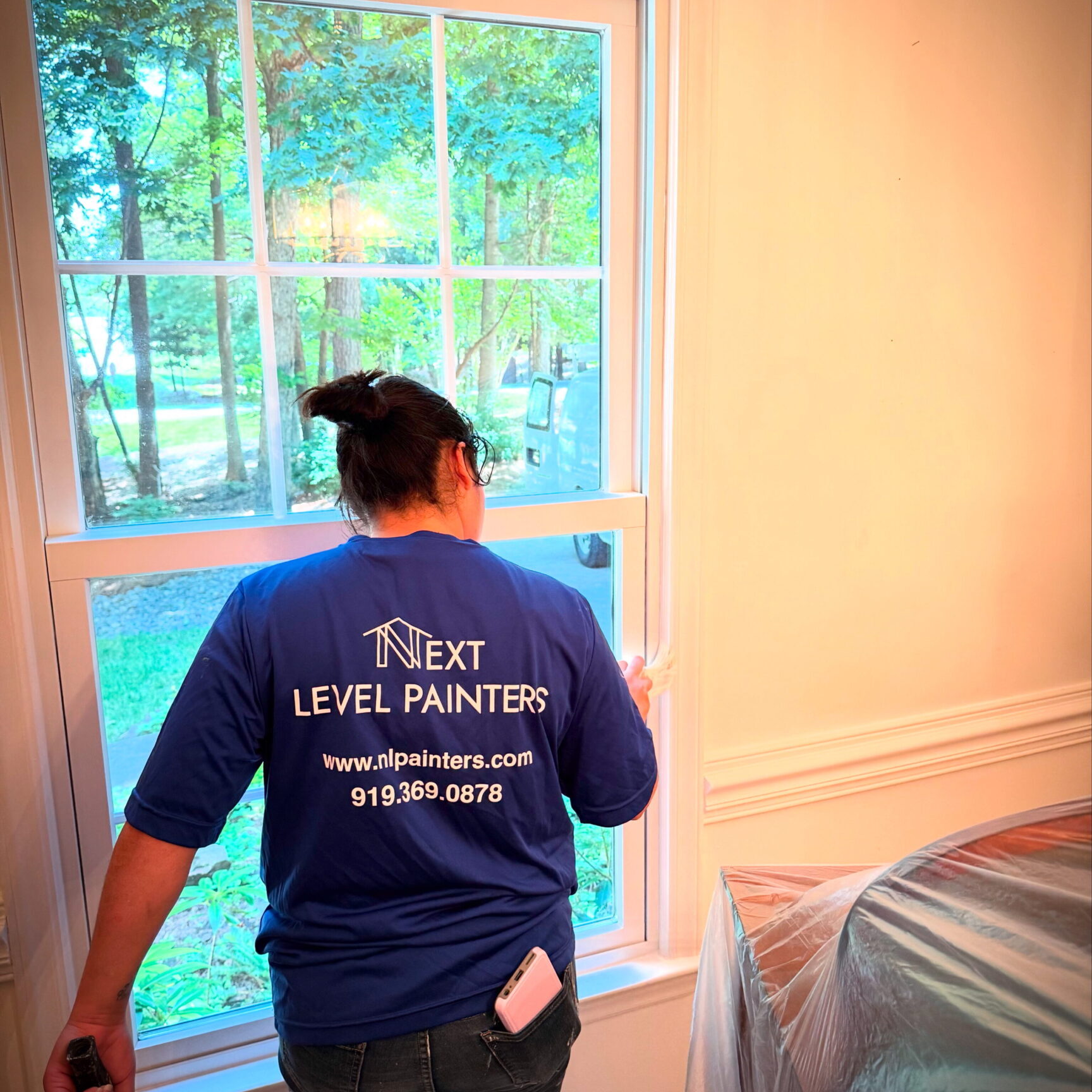Painter working indoors near a window with natural light.