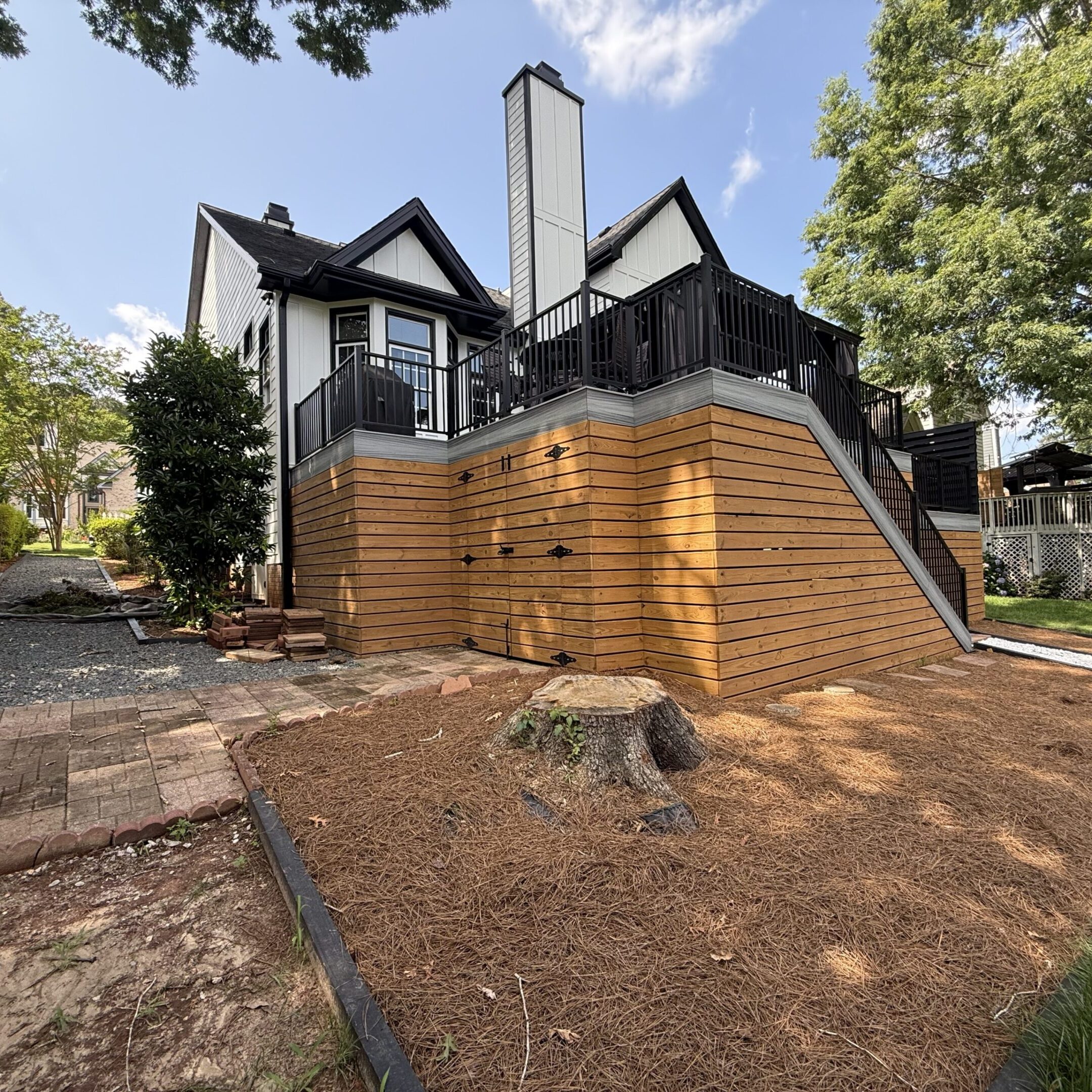 A house with a newly built wooden retaining wall around its foundation.