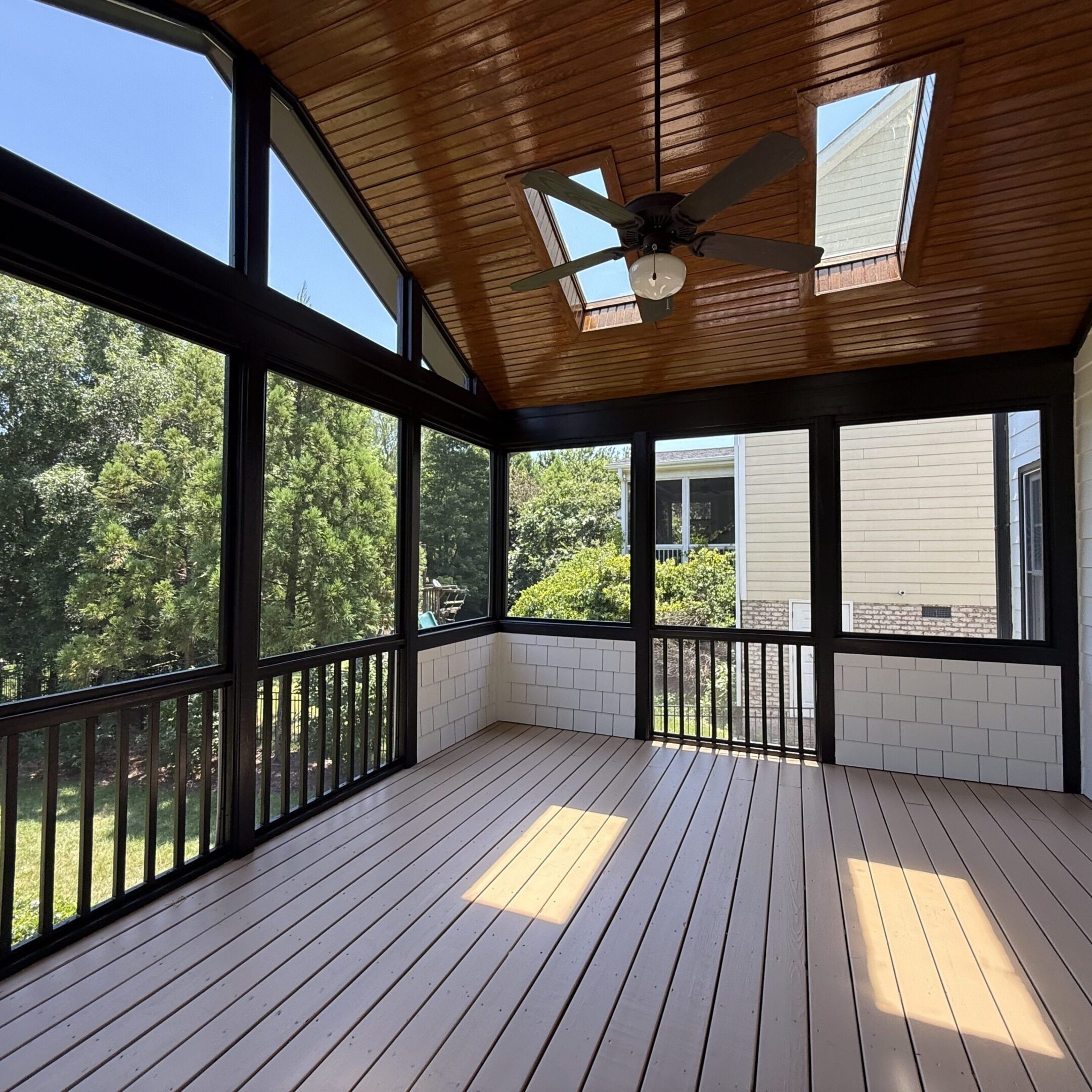 Bright screened porch with wooden ceiling and floor.