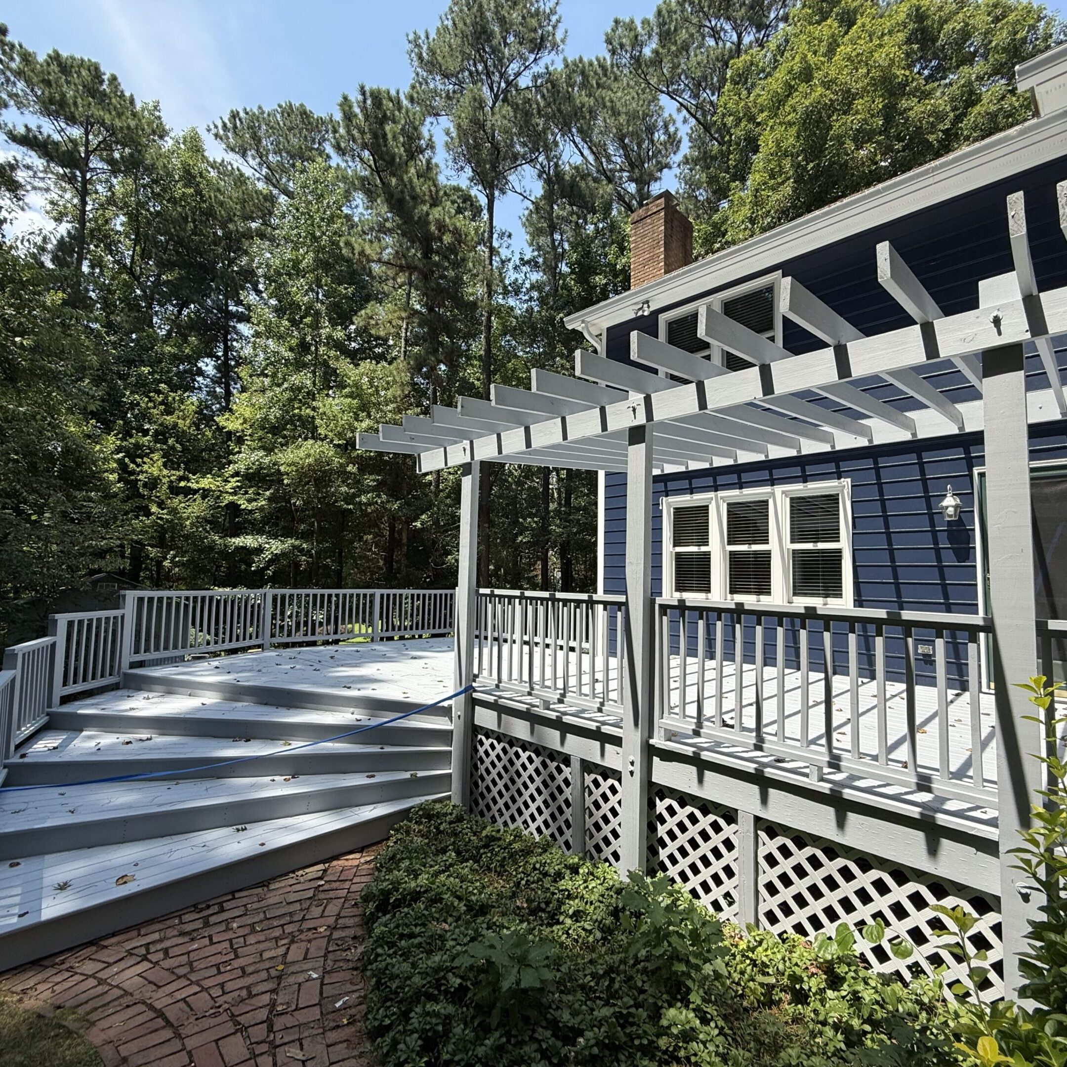 Cozy gray house with a spacious deck surrounded by trees.